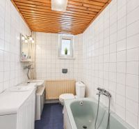 Fürdőszoba csempékkel, kék padlóval, káddal és fa mennyezettel egy családi házban.