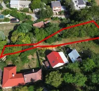 Légi felvétel a kolačnai kertekben található telkekről, amelyeket zöldterületek és házak vesznek körül.