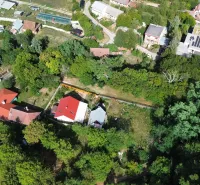 Légi felvétel a Kolačnában található kertekről, elszórtan elhelyezkedő házakkal és buja növényzettel.