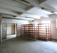Gyártóhelyiségek polcokkal és lifttel, ablakokkal megvilágítva, kerámia padlóval.