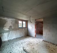 Családi ház belső tere befejezetlen vakolattal és betonpadlóval.