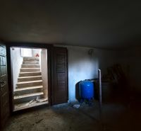 Kerti tároló egy családi házban betonlépcsőkkel és kék tartállyal.