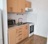 Konyha egy kétszobás lakásban fa mintázatú padlóval, mikrohullámú sütővel és tűzhellyel.