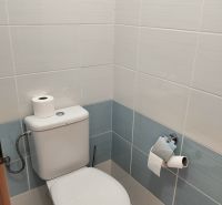 Világos csempékkel és WC-vel ellátott fürdőszoba egy kétszobás lakásban.