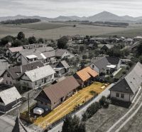 Családi házak madártávlatból a mezők és hegyek által körülvett Zsabokrek településen.
