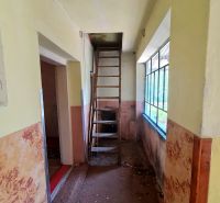Keskeny folyosó a padlásra vezető létrával egy családi házban.