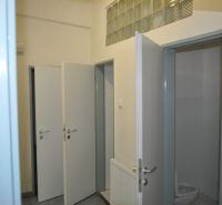 Nyitott ajtó a gyártóhelyiségben lévő mosdóban, csempével és mosdókagylóval.