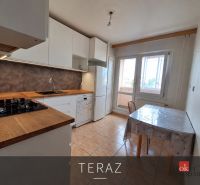 Nappali fa dekoros padlóval és narancssárga kanapéval egy háromszobás lakásban.