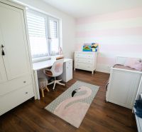 Gyerekszoba fehér bútorokkal és fa dekor padlóval egy családi házban.