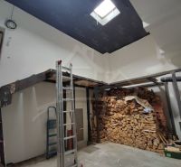 Családi ház fa gerendákkal és tárolt fával a belső térben.