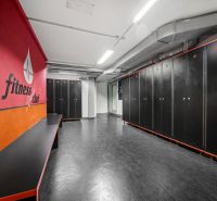 Fitnesz öltöző fekete szekrényekkel és piros fallal az üzlethelyiségben.