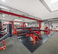Fitneszközpont edzőgépekkel, padokkal és tükrökkel a kereskedelmi helyiségekben.