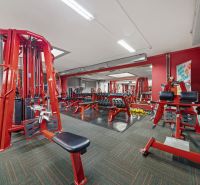 Fitneszközpont piros edzőgépekkel és súlyzókkal, üzlethelyiségek.