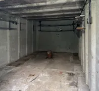 Betongarázs Pozsony-Újvárosban, egyszerű falakkal és tárolópolcokkal.