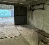 Garázs belső tér betonpadlóval és fém polcokkal.
