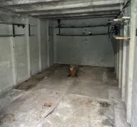 Garázs belső tér betonfalakkal és tárolópolcokkal.