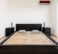 Hálószoba egy kétszobás lakásban fekete ággyal és éjjeliszekrényekkel.
