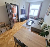 A háromszobás lakás nappalija kényelmes ülőgarnitúrával és fa mintázatú padlóval rendelkezik.
