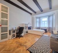 Hálószoba egy háromszobás lakásban, fa dekoros padlóval és mennyezeti gerendákkal.