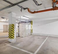 Négy szobás lakás földalatti parkolóhelye sárga biztonsági csíkokkal és csövekkel.