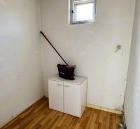 Kis szoba ablakkal, szekrénnyel és fa mintázatú padlóval egy családi házban.