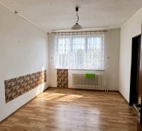 Egy szoba családi házban fa dekorációjú padlóval, függönnyel és radiátorral az ablak alatt.