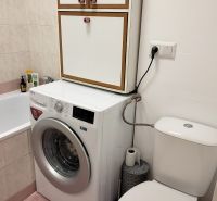 Egy szobás lakás fürdőszobája mosógéppel, káddal és WC-vel.