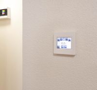 Állítható termosztát a garzonlakás falán, egyszerű dizájn, fehér háttér.