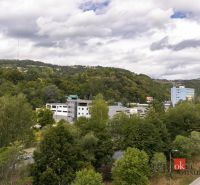 Kilátás a zöldövezetre és épületekre Besztercebányán, az Északi utcán, dombokkal körülvéve.
