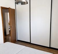 Hálószoba egy háromszobás lakásban lámpával, gardróbszekrénnyel és fa dekorációjú padlóval.