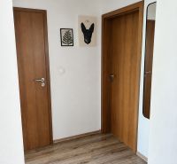 Folyosó egy 3 szobás lakásban, fa dekorációjú padlóval és fa ajtókkal.