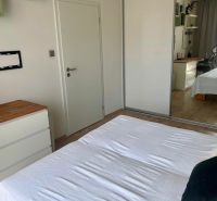Hálószoba egy kétszobás lakásban fehér ággyal és fa dekorációjú padlóval.