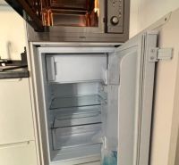 Konyhapult mikrohullámú sütővel és nyitott hűtőszekrénnyel. Fa dekoros padló.