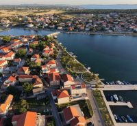 Légi felvétel Nin városának part menti területéről, villák tetejével és kikötővel.