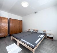 Hálószoba ággyal, fa szekrényekkel és fa dekorációjú padlóval egy háromszobás lakásban.