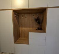 Fehér beépített szekrény fa dekorációval és fogasokkal a kétszobás lakásban.
