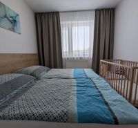 Világos hálószoba ággyal és gyerekággyal egy kétszobás lakásban.