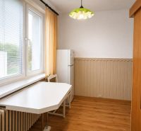 Konyha egy kétszobás lakásban asztallal, székkel, hűtőszekrénnyel és fa dekorációjú padlóval.