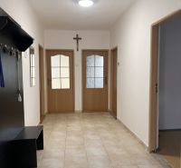 Folyosó egy családi házban csempével, faajtókkal és fogassal.