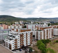 Kilátás a Nobelova utcai lakóházakra Pozsony - Újvárosban, amelyeket zöldterületek és dombok vesznek körül.