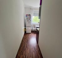 Keskeny folyosó fa dekorációs padlóval vezet a konyhába egy kétszobás lakásban.