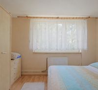 Hálószoba ággyal, szekrénnyel és fa dekorációjú padlóval egy családi házban.