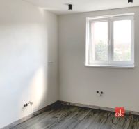 Egyszobás lakás egyszerű szobája fa dekor padlóval és fehér falakkal.