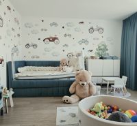 Gyerekszoba játékokkal, kék ággyal, autós tapétával és fa dekorációjú padlóval.