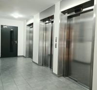 Egy négy szobás lakás folyosója négy fém lifttel és szürke csempével.
