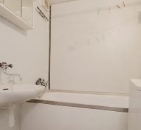 Fürdőszoba egy kétszobás lakásban káddal, mosdóval és mosógéppel.