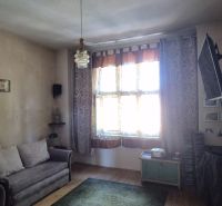Nappali egy kétszobás lakásban kanapéval, TV-vel és fa dekorációjú padlóval.