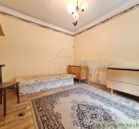 Szoba ággyal, székkel és szőnyegekkel, fa dekorációjú padlóval, sarokbútorral.