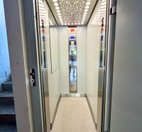 Lift világított mennyezettel és világos falakkal egy lakóházban.