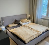 Hálószoba nagy ággyal, éjjeliszekrényekkel és fa dekorációs padlóval egy háromszobás lakásban.